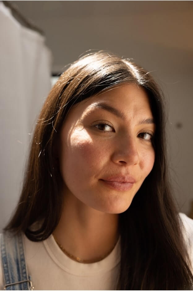 Brunette woman with long hair, facing to the side, face turned towards the camera.