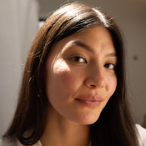 Brunette woman with long hair, facing to the side, face turned towards the camera.