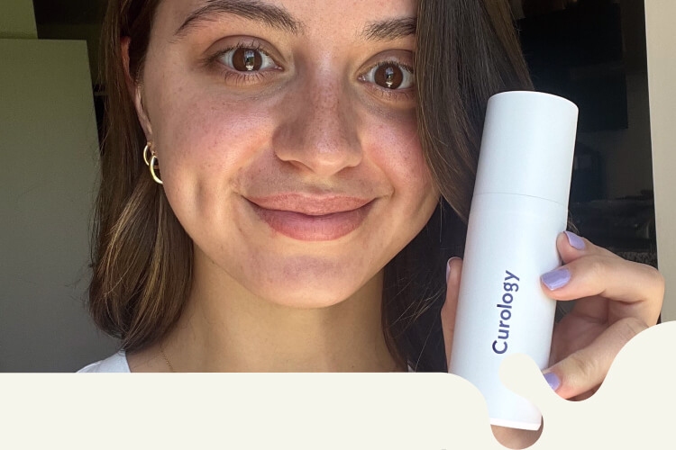 Brunette woman smiling, wearing a white top, holding up a white Custom Formula Curology bottle in her left hand.